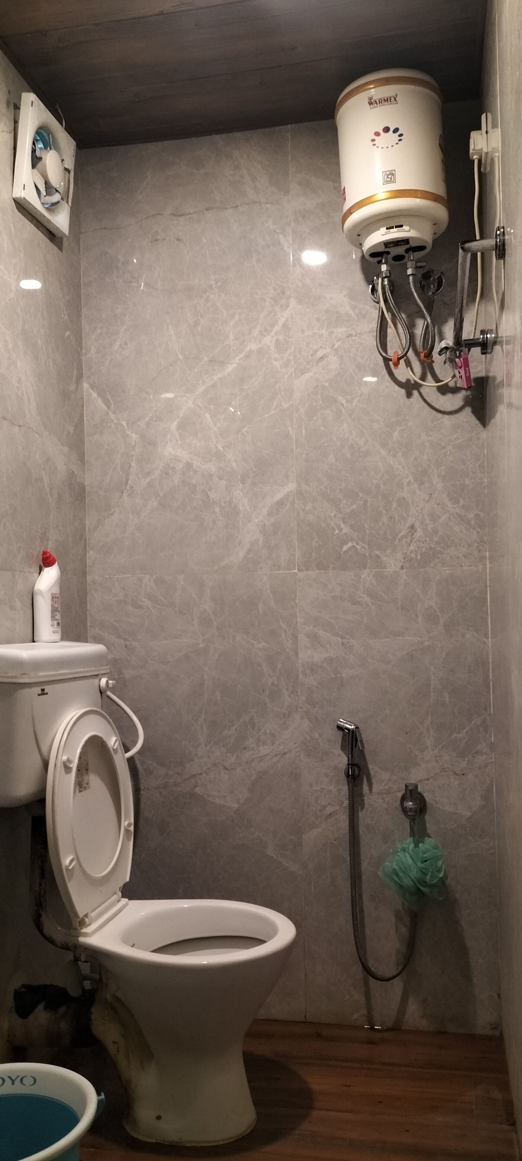A bathroom with a toilet, a water heater, and a shower.