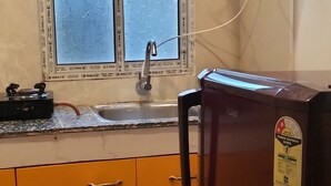 A kitchen with a refrigerator, a window with frost, a sink, and a water dispenser.