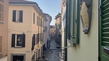 Una stretta strada acciottolata fiancheggiata da edifici con persiane e un rilievo in pietra su una parete.
