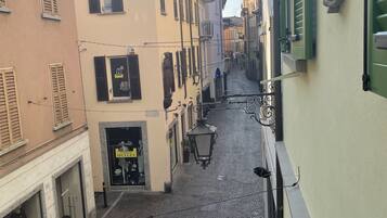 A narrow cobblestone street lined with buildings featuring traditional shutters and a storefront with mannequins.