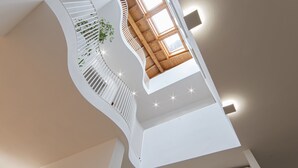 Un interior moderno con una escalera curva, techo de madera y un ventanal grande.