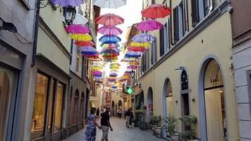 A cobblestone street with colorful umbrellas hanging overhead.