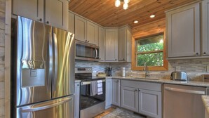 A modern kitchen with stainless steel appliances, a microwave, and a large window providing natural light.