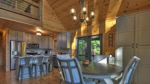A spacious kitchen with a central island, bar stools, and a dining table with chairs.