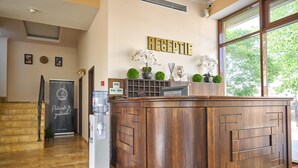 A reception area with a wooden reception desk, a water dispenser, and a sign that reads "RECEPTION". - Hotel Alma (Constanta)