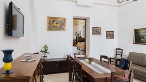 A dining area with a wooden table, chairs, and a television mounted on the wall.