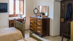 A bedroom with two beds, a dresser, a mirror, and a television on the wall.