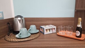 A kitchenette with a coffee maker, two cups, a box of tea, two glasses, and a bottle of wine on a tray. - B (Napoli)