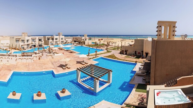 Et resort med flere swimmingpools, et spabad og udsigt til stranden.