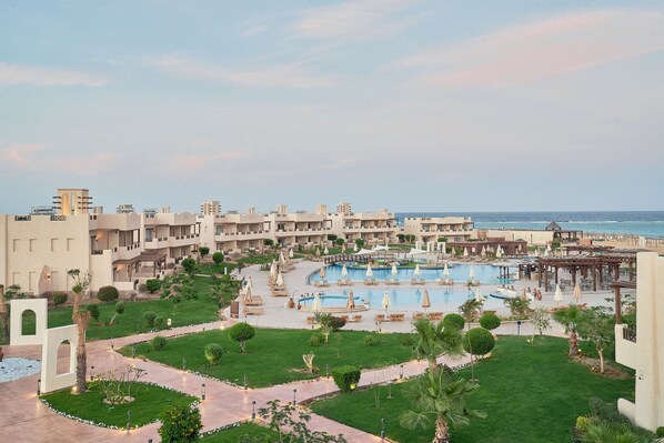 Relax by the pool surrounded by lush greenery and palm trees, with a scenic view of the adjacent water.