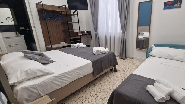 Quarto de hotel com duas camas, um guarda-roupa, uma televisão e um espelho.
