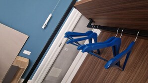 Quarto com guarda-roupa de madeira, cadeira suspensa azul e mesa de cabeceira branca.