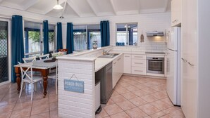 A modern kitchen with white cabinetry, a built-in oven, and a dishwasher. - Beach Retreat - Family & Pet Friendly + only 400m from beach (Quindalup)