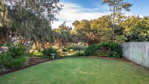 A well-maintained backyard with a lawn, various shrubs, and trees. - Beach Retreat - Family & Pet Friendly + only 400m from beach (Quindalup)