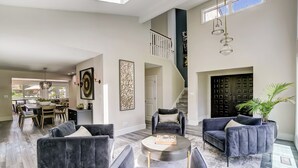 Un salón comedor espacioso con techo alto y una escalera que conduce a un nivel superior.