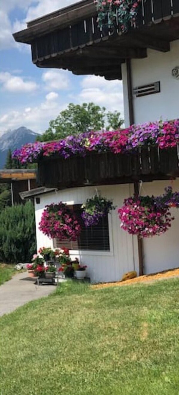Traditional chalet-style building with a sloped roof and wooden beams, set amidst lush green surroundings.