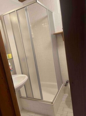 Bathroom features a glass-enclosed shower area with a clear glass door and a white sink.