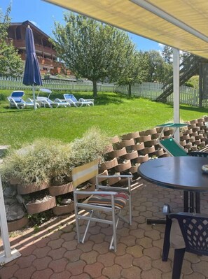 Relax in a serene outdoor space with a covered seating area featuring lounge chairs and a table.