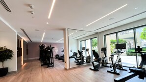 A modern gym with various exercise equipment, large windows, and a clean, well-lit interior. - Luxury Burj Royale Full Burj Khalifa & Fountain Views (Dubai)
