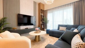 A modern living room with a flat-screen TV, a sofa, a coffee table, and a bookshelf.