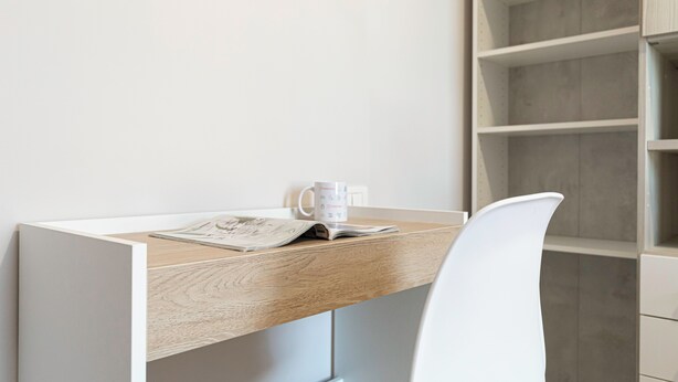 Un escritorio moderno y minimalista con superficie de madera, una taza blanca y una revista.