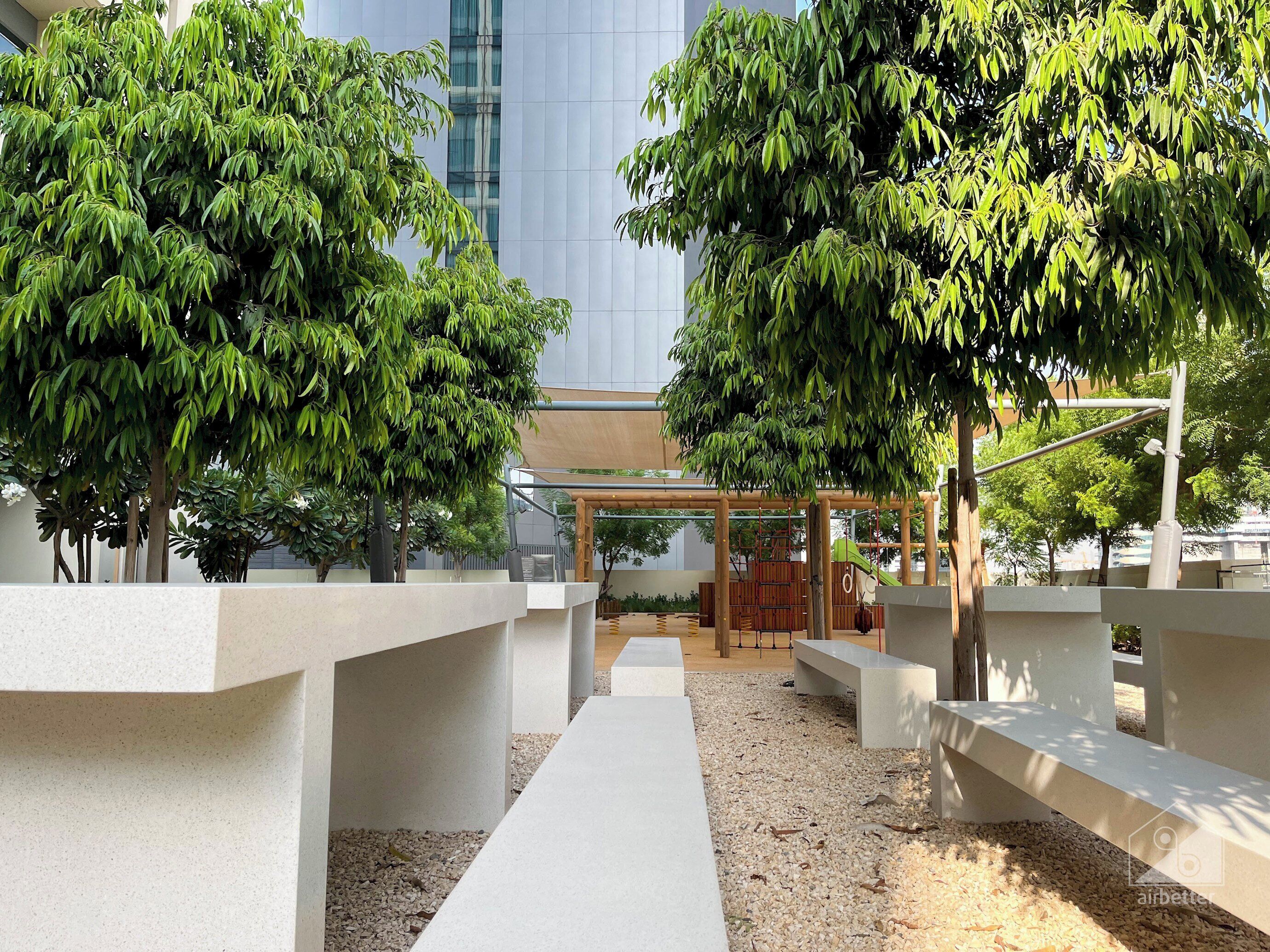 A modern outdoor area with concrete planters, a wooden pergola, and a playground structure.