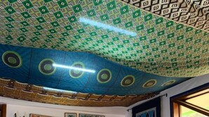 Quarto com teto estampado, obras de arte nas paredes e mesa redonda de madeira com cadeiras.