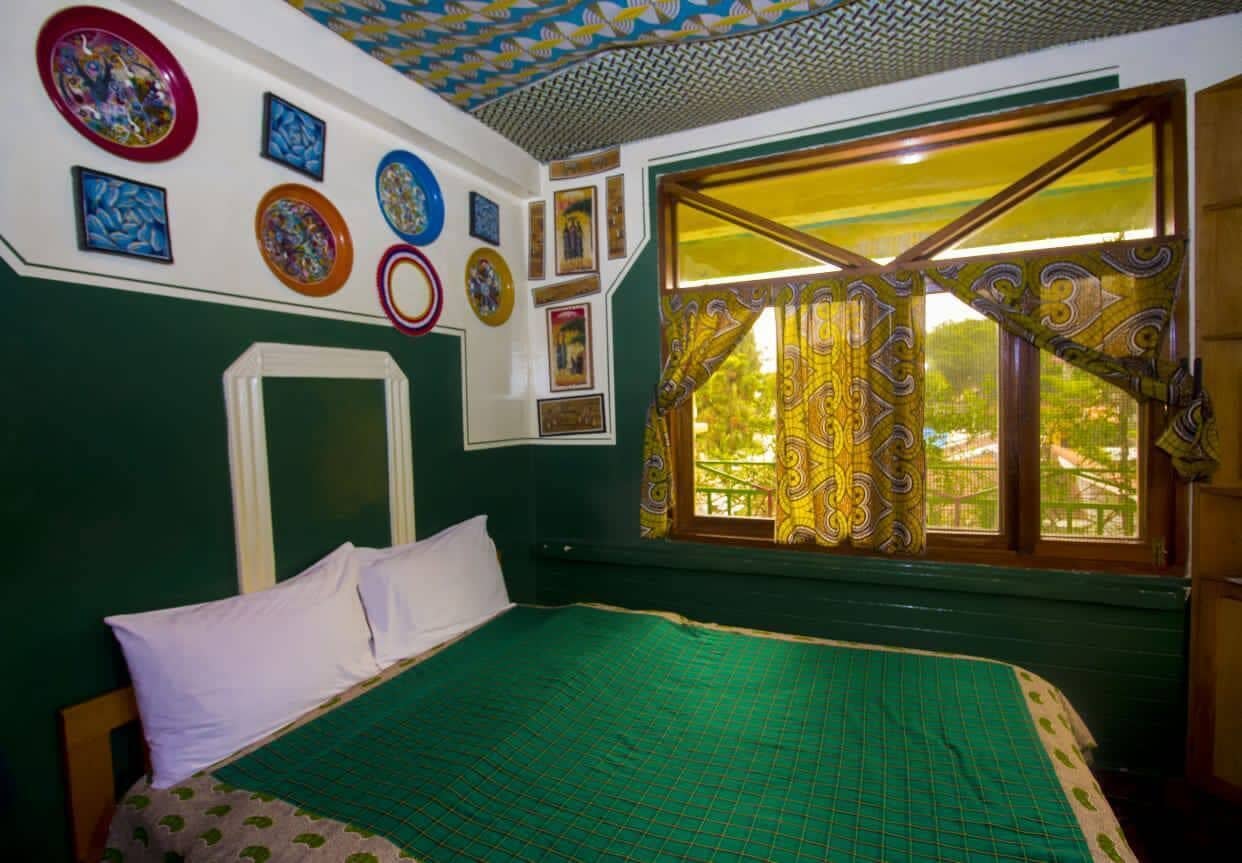 Una habitación con cama, ventana con cortinas y adornos en la pared.