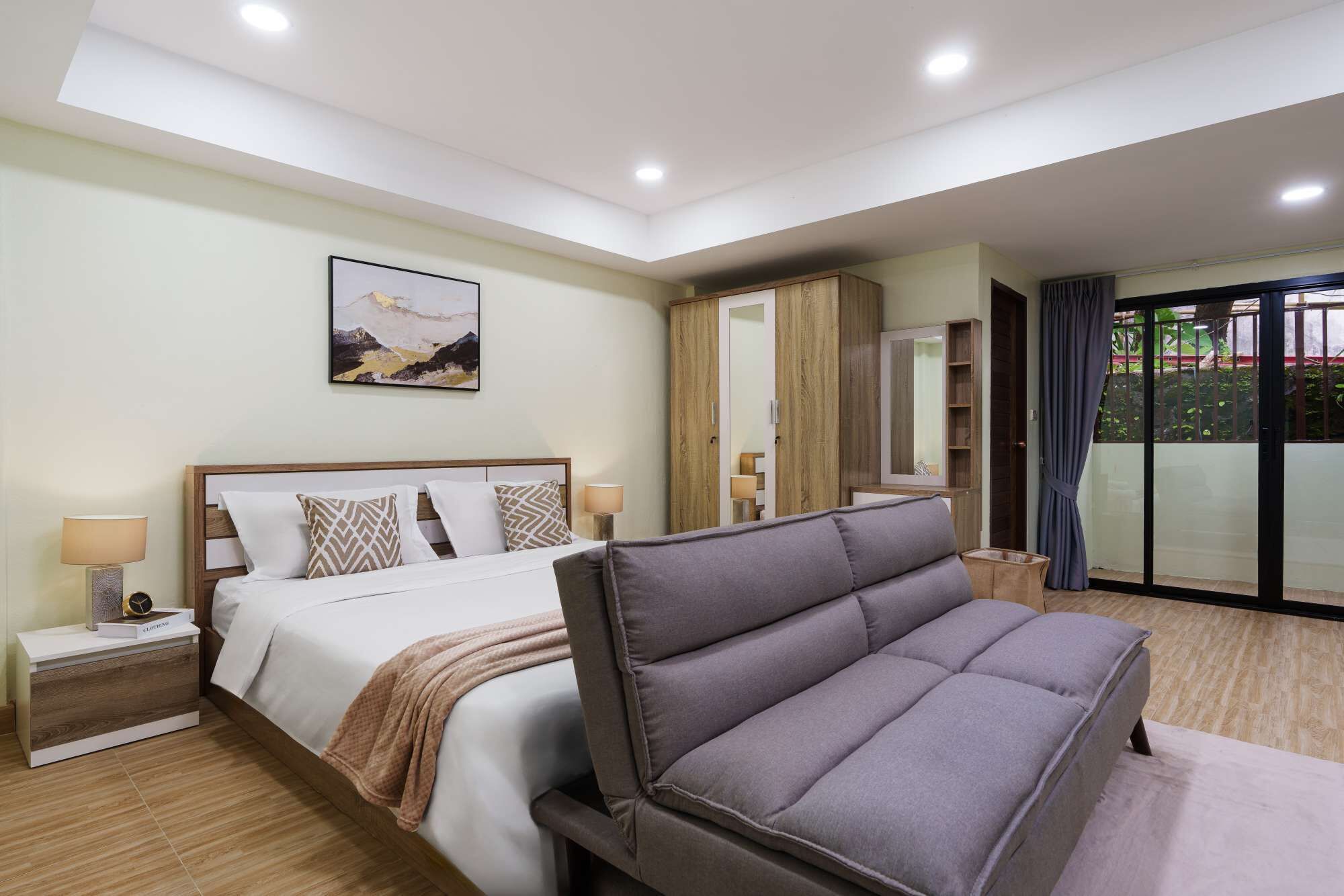 Een moderne slaapkamer met een bed, nachtkastjes, een bank, een kledingkast en een groot raam met gordijnen.
