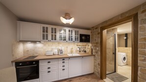 A compact kitchen with white cabinets, a built-in oven, and a stone wall.