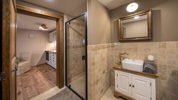 A modern bathroom with a glass shower enclosure, a wooden vanity, and a beige tiled backsplash.