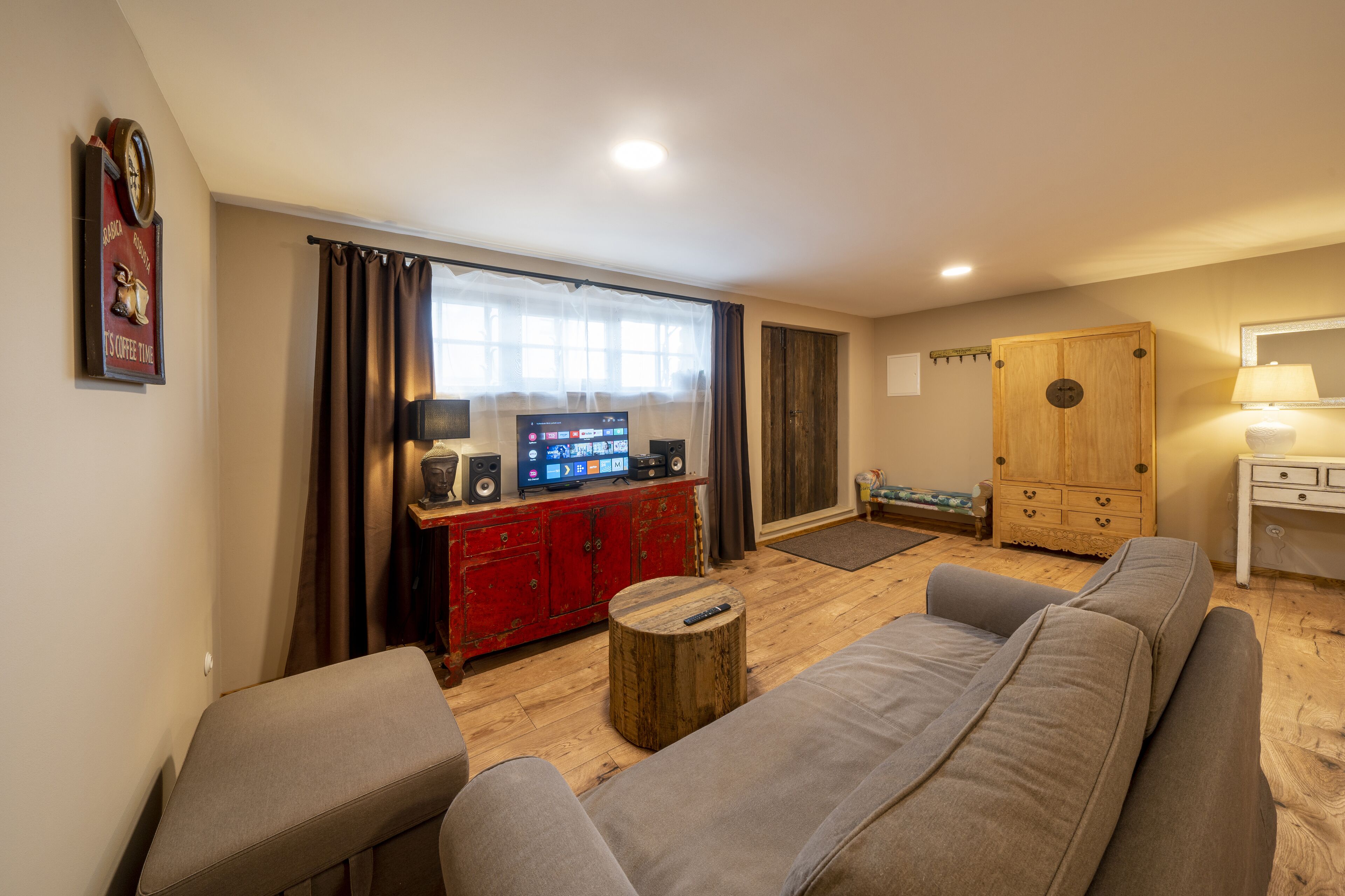 A living room with a sofa, a red entertainment unit, a wooden cabinet, and a television.