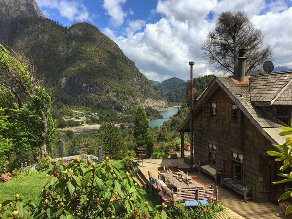 Une cabane en bois dotée d’une terrasse offrant une vue sur une vallée et un lac.