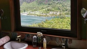Een badkamer met twee wastafels, een raam met uitzicht op een bergachtig landschap, en een spiegel.