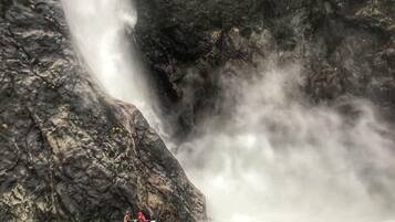 Un grupo de personas haciendo kayak en un río, con una cascada al fondo.