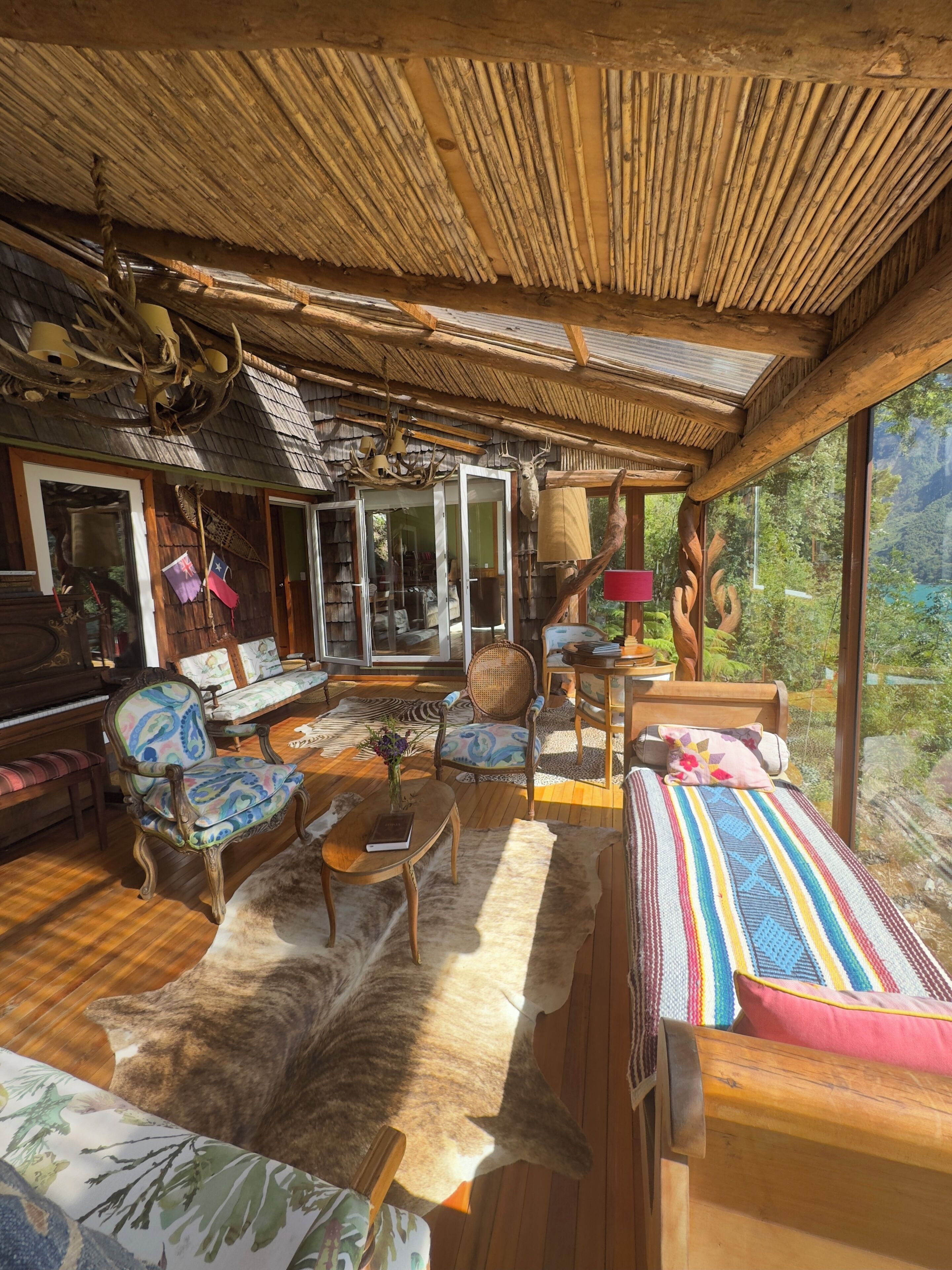 Un interior rústico con techo de paja, muebles de madera y un gran ventanal con vistas al exterior.