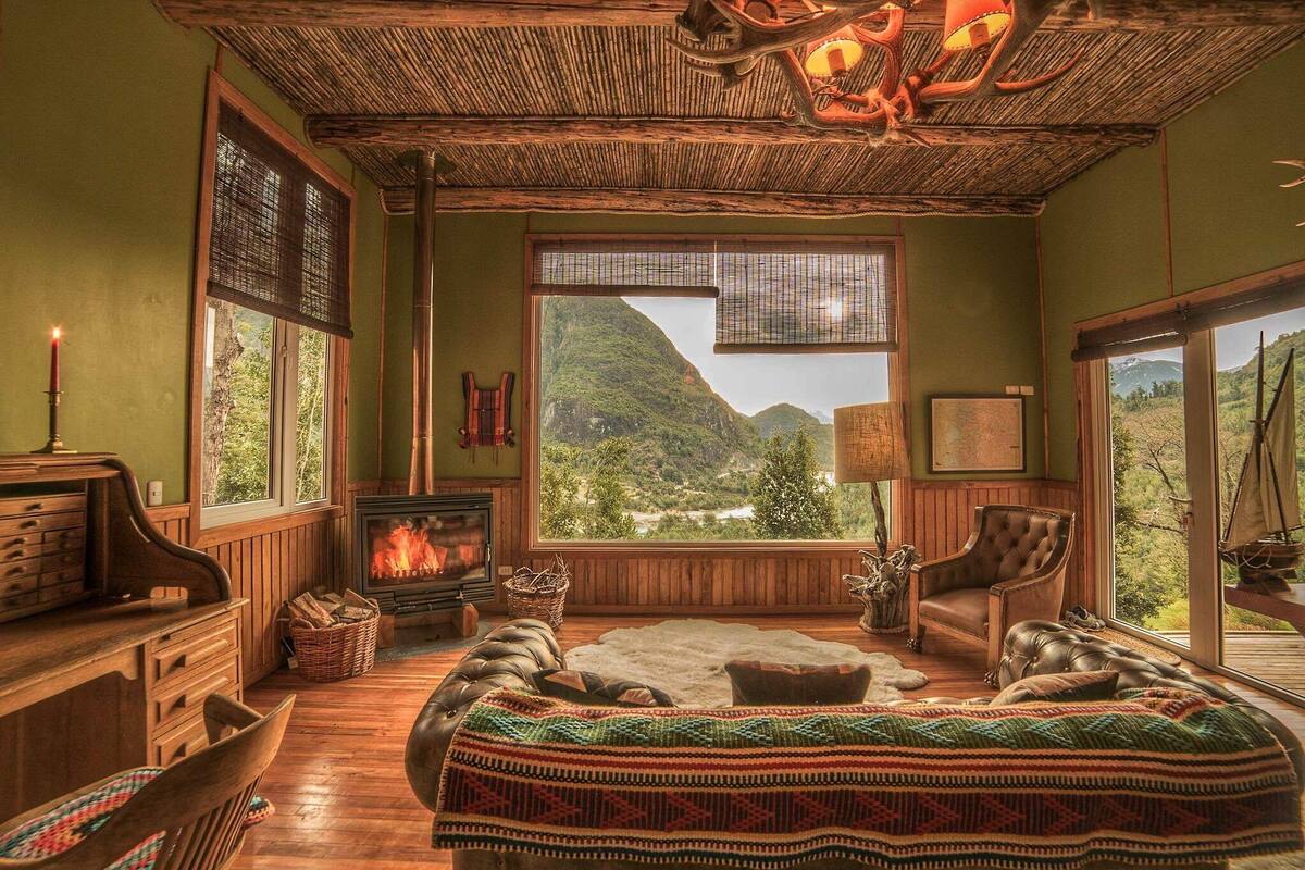 Um quarto aconchegante com lareira, janelas amplas, cama e vista para as montanhas.