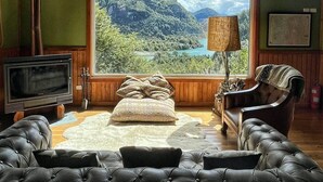 Een kamer met een groot raam, een televisie, een open haard en een leren bank.
