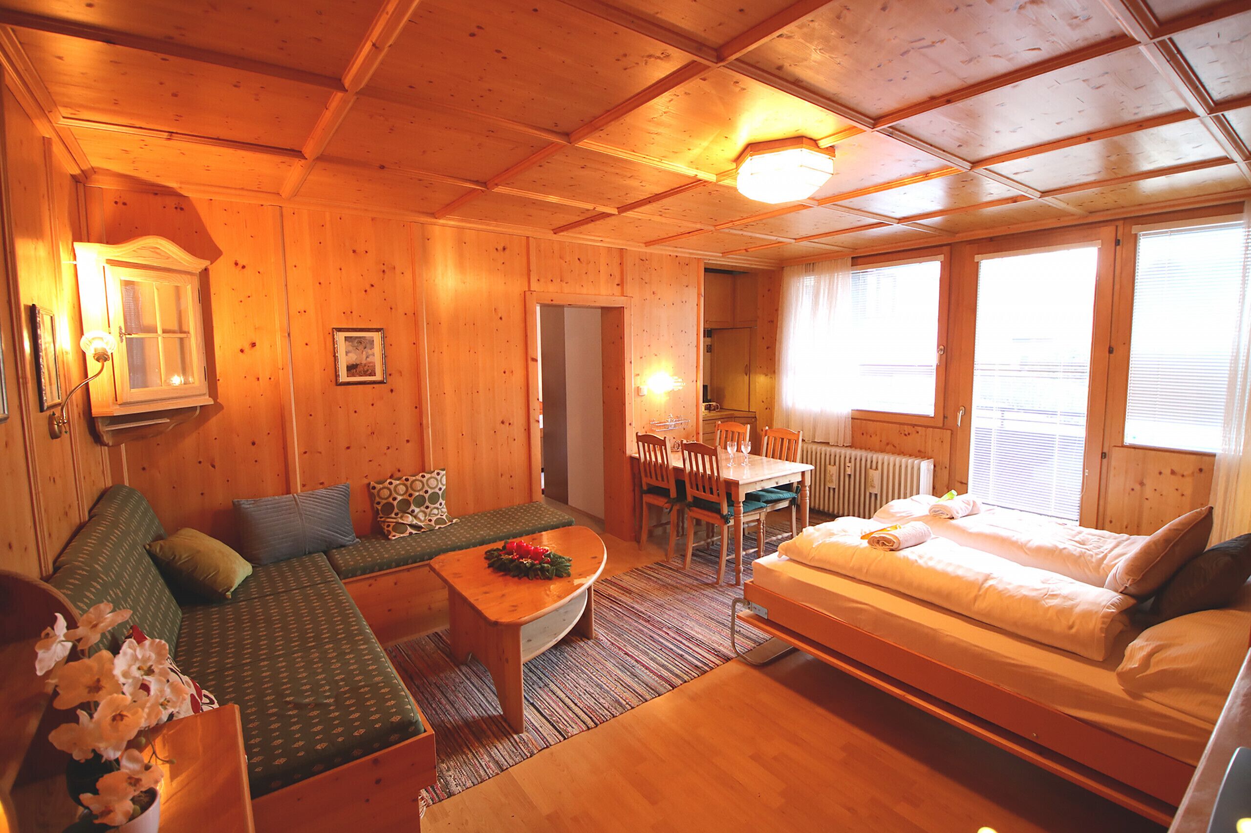 A cozy cabin interior with a sofa, a dining table, and a bed.