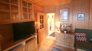 A wooden-paneled room with a television, cabinets, a sofa, and a small table with a plant. - Cosy Retreat Apartment -Top 39 (Kaprun)