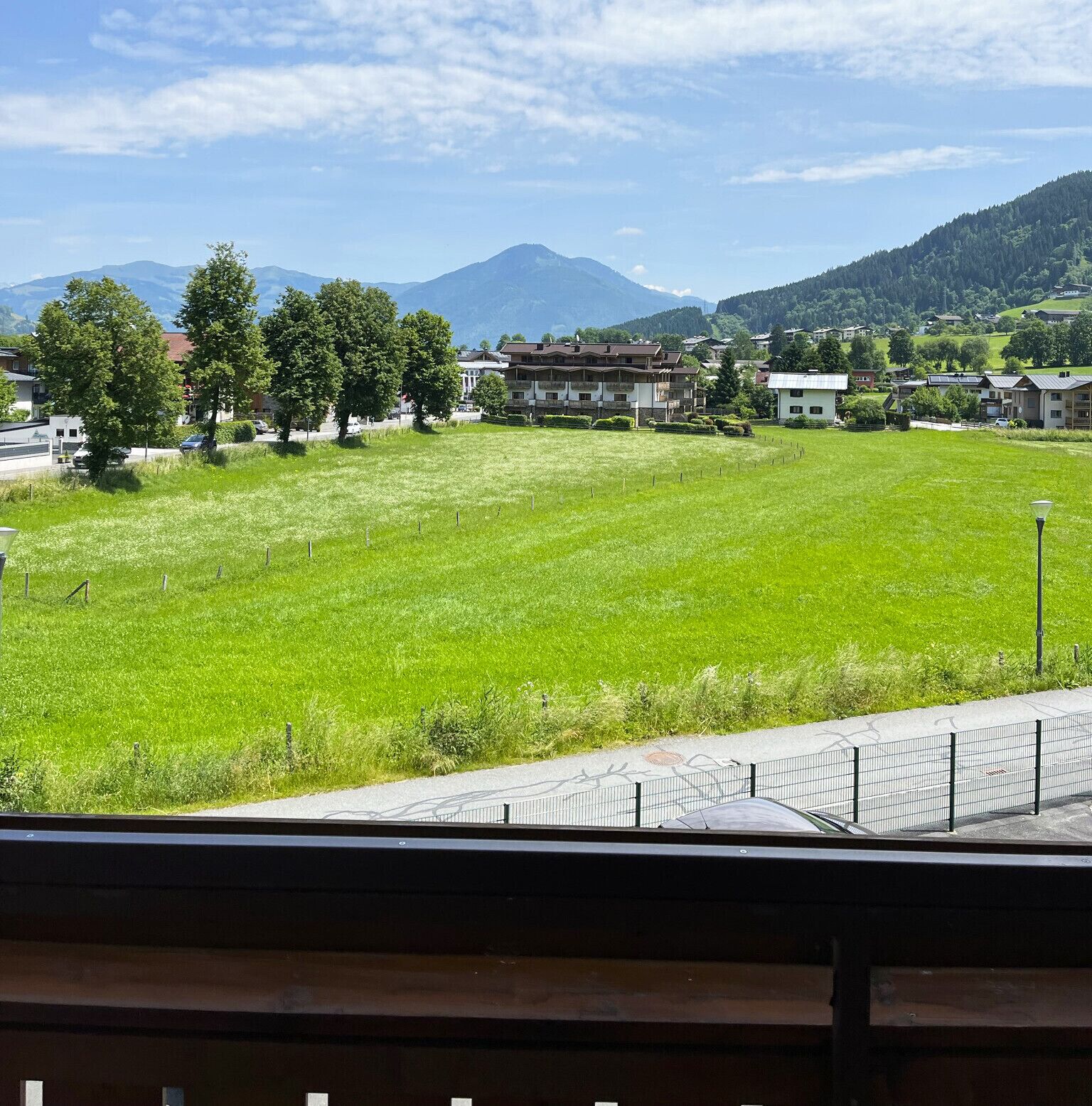 A grassy field with a building in the background and mountains in the distance.