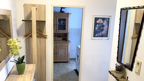 A hallway with a wooden cabinet, a green potted plant, a mirror, and a tiled floor.
