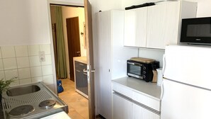 A compact kitchen with a stove, microwave, and white cabinets.