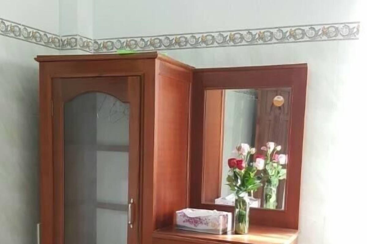 Ein Holzschrank mit Spiegel und einem kleinen Kühlschrank darunter.