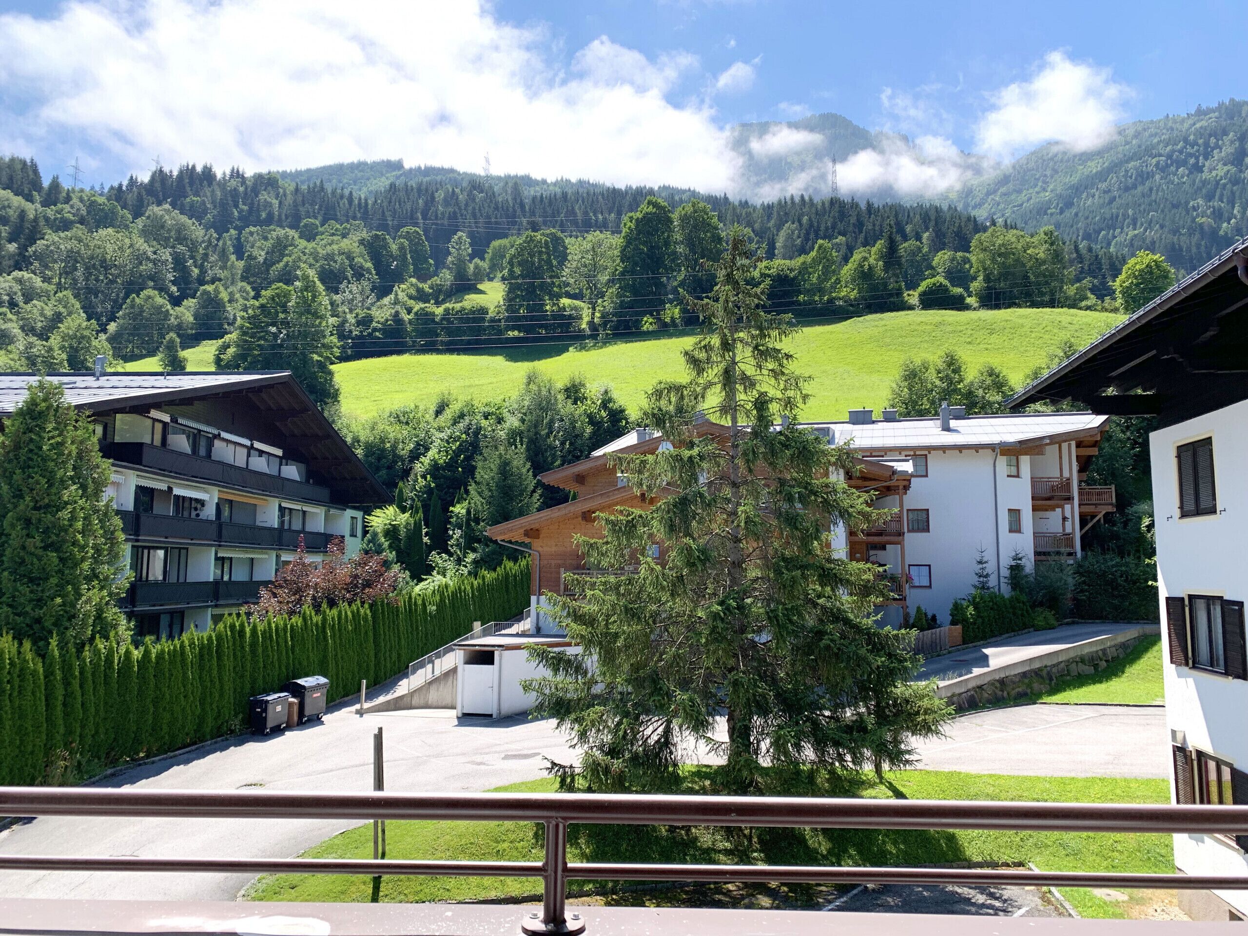A residential area with modern buildings, a clear sky, and a green valley.