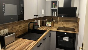 A compact kitchen with a built-in microwave, a toaster, a sink, and a dishwasher.