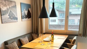 A dining area with a wooden table, cushioned benches, and pendant lighting.
