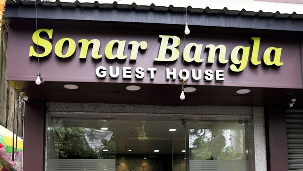 A guest house named Sonar Bangla with a modern design, large glass windows, and a visible interior with a ceiling fan. - Sonar Bangla Guest House (Kolkata)