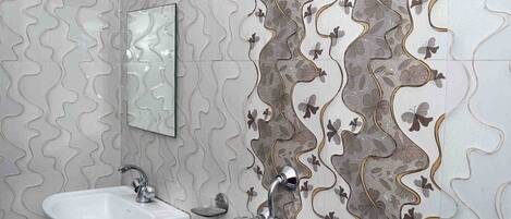 A bathroom with a sink, mirror, shower, and patterned tiles.