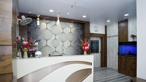 A reception area with a modern design, featuring a white reception desk, decorative wall panels, and a large aquarium. - Sonar Bangla Guest House (Kolkata)